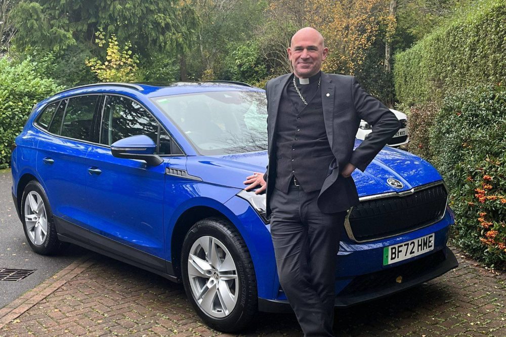 Bishop Pete next to blue car