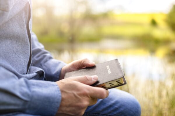man reading book by river