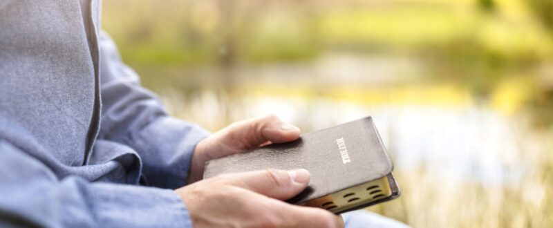 man reading book by river