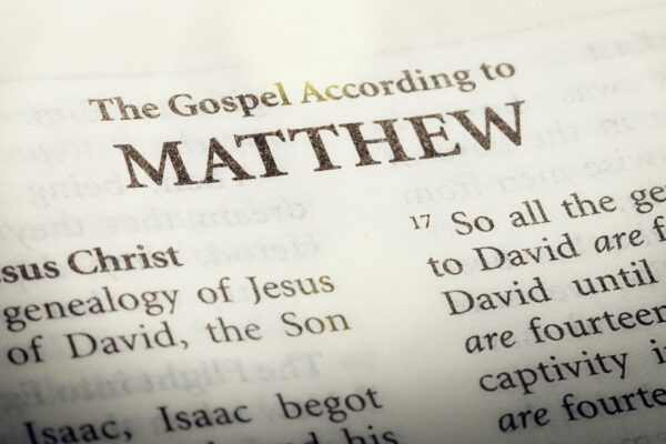 A copy of the Bible is open to the title page of ther first book of the New Testament, the Gospel according to Matthew.