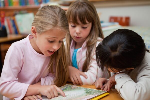 Schoolgirls reading a book together in a classroom