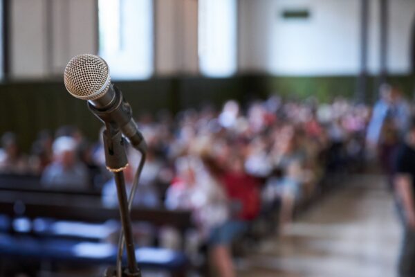 Close up of microphone on a podium in an auditorium. Microphone and abstract blurred conference hall or seminar room background