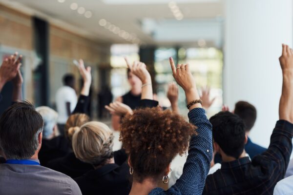 Shot of a group of businesspeople raising their hands to ask questions during a conference