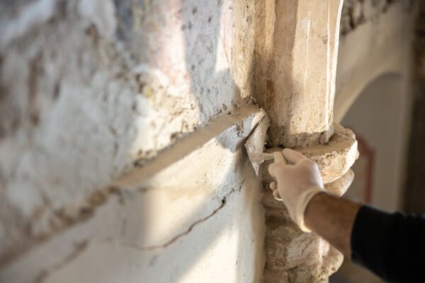 Close-up of Repairing Damaged Wall with Trowel in Antique Chapel