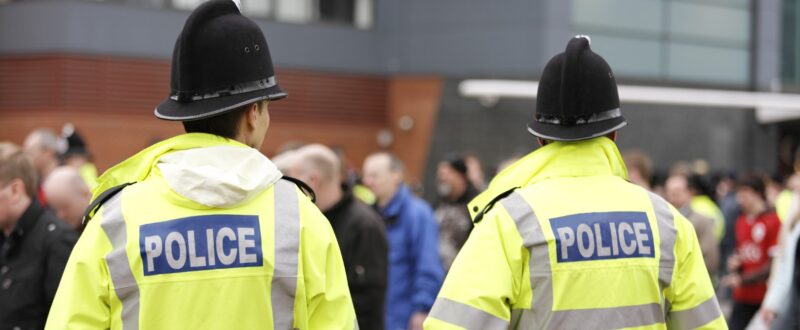 Two British Policemen-Traditional Helmets-Crowd Control. More below...