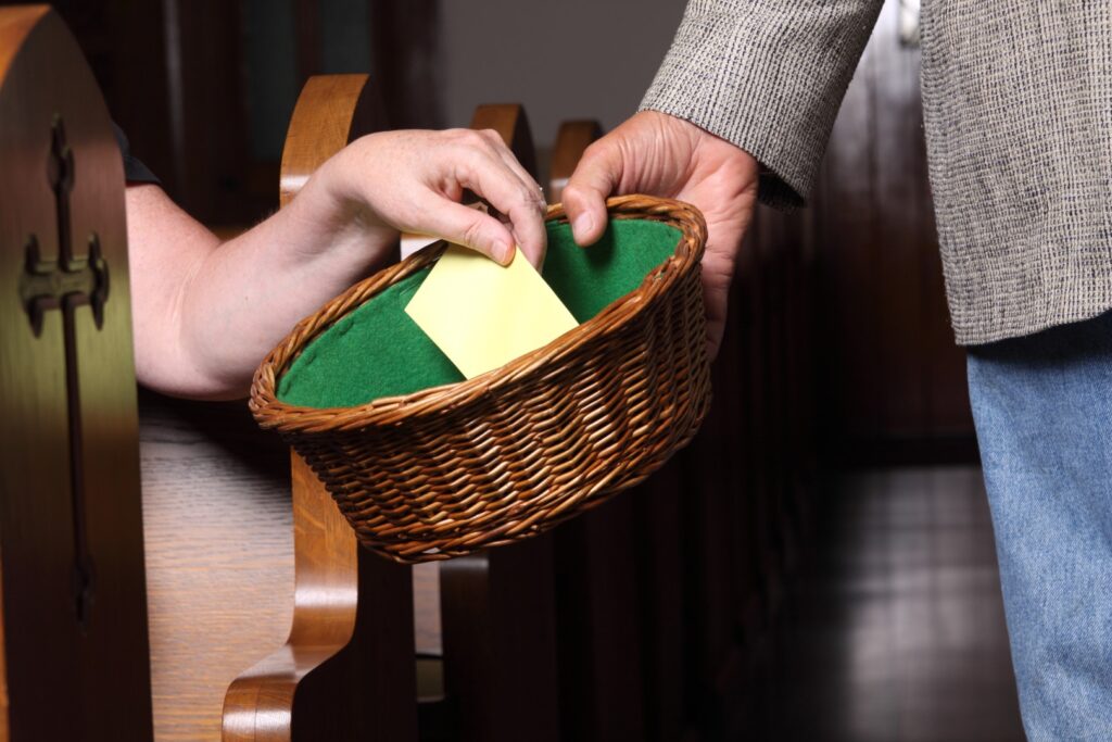 Woman's hand putting an envelope in the collection basket