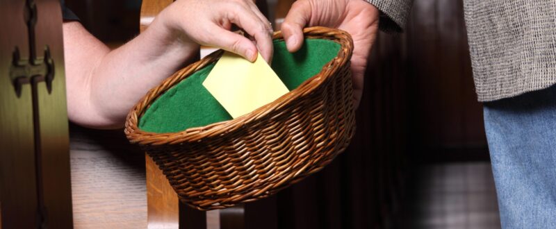 Woman's hand putting an envelope in the collection basket