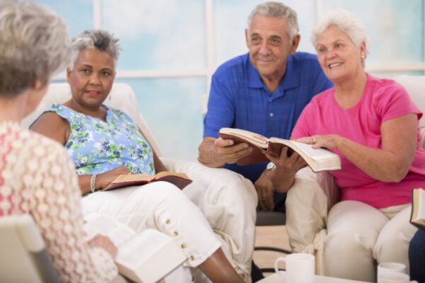 Selective focus on bibles. Group of senior adults during a bible study. Multi-ethnic group reading bible together.