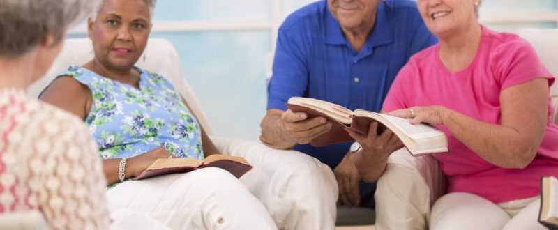 Selective focus on bibles. Group of senior adults during a bible study. Multi-ethnic group reading bible together.