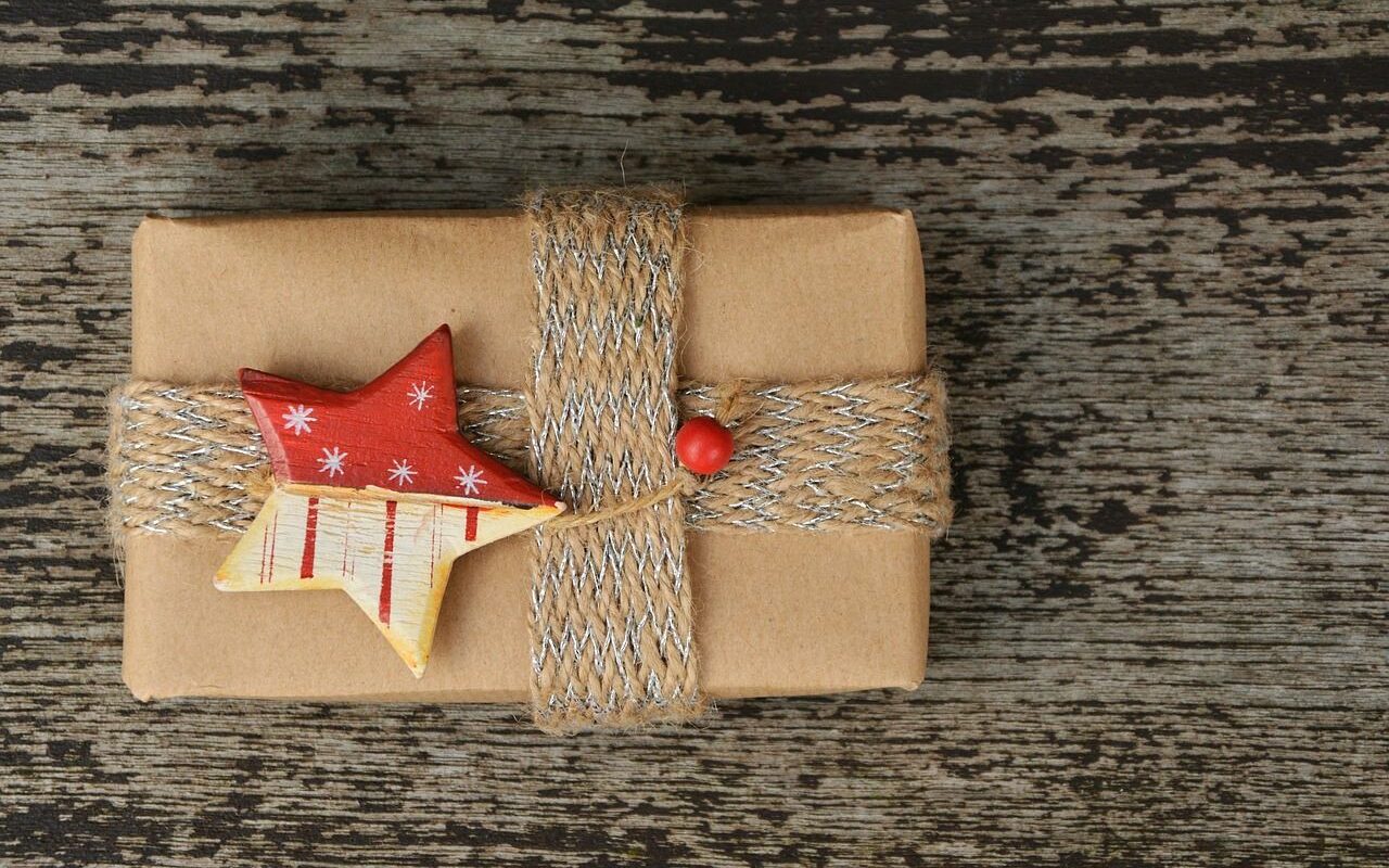 Present wrapped in brown paper with woven string wrapped around it and a wooden painted star placed in the centre