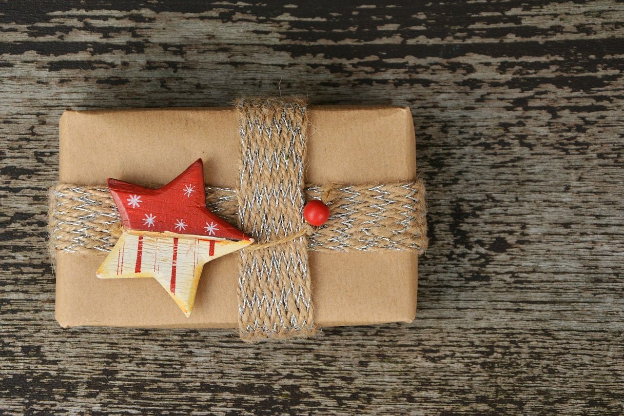 Present wrapped in brown paper with woven string wrapped around it and a wooden painted star placed in the centre
