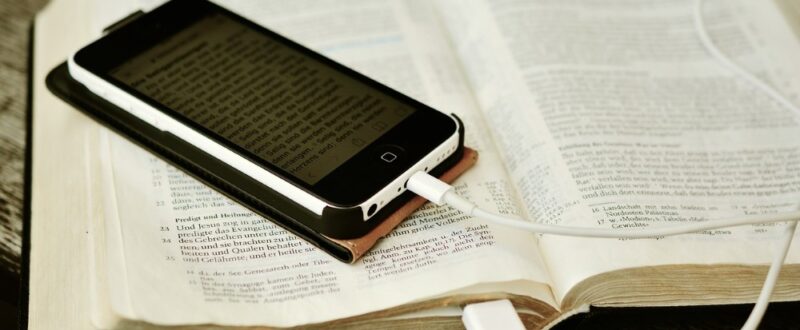 open bible with an iphone on top displaying a part of the bible in German