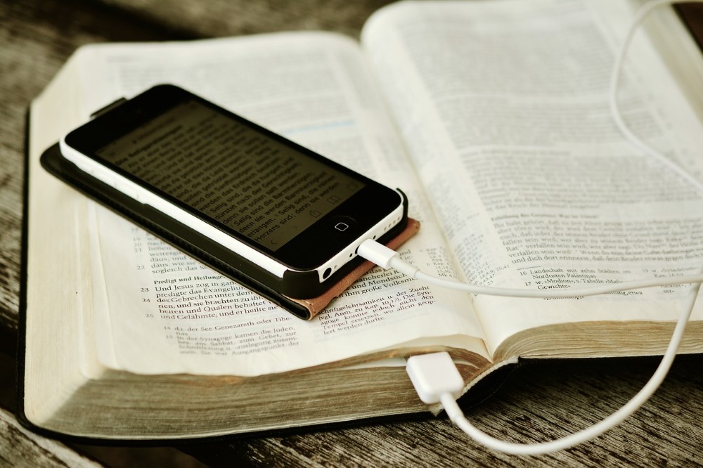 open bible with an iphone on top displaying a part of the bible in German