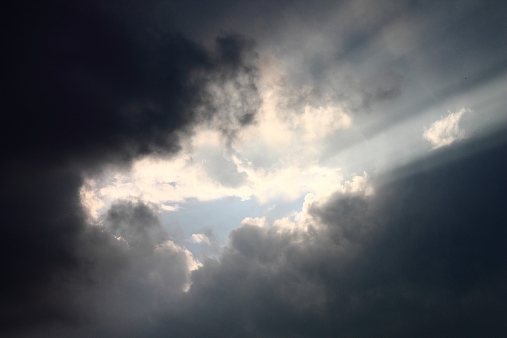 Dark clouds with sunlight shining through from the middle to top left