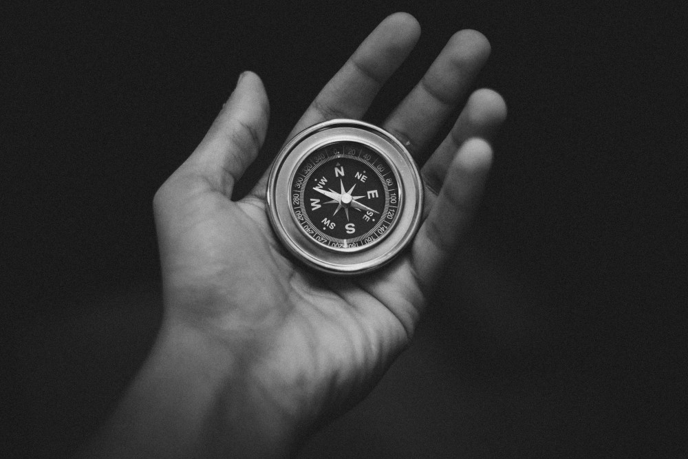 black and white photo of a hand holding a compass