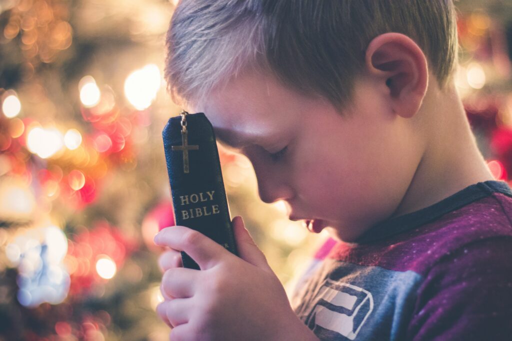 Child holding a bible and holding head down to pray