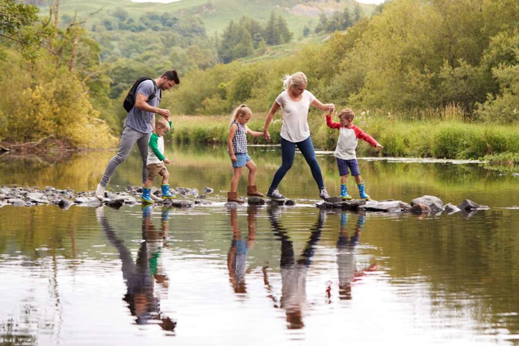 family crossing river on hike