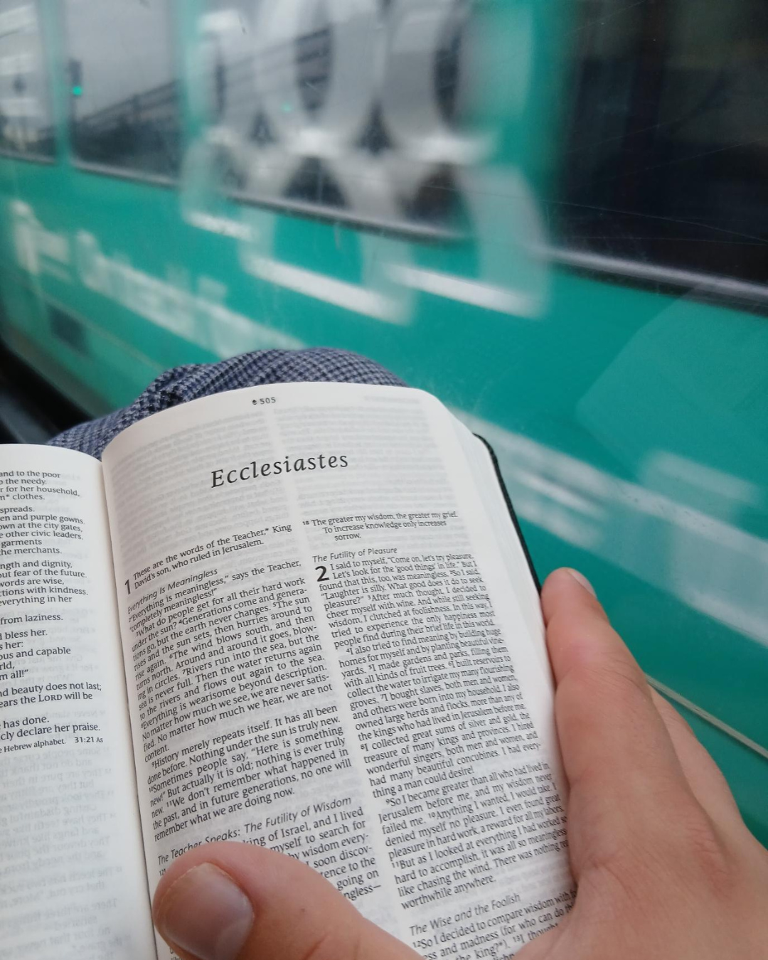 Someone is holding a Bible open at the beginning of Ecclesiastes. A train is going by in the background.